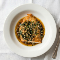 Skate Wing dish with capers on a white plate with a fork beside it